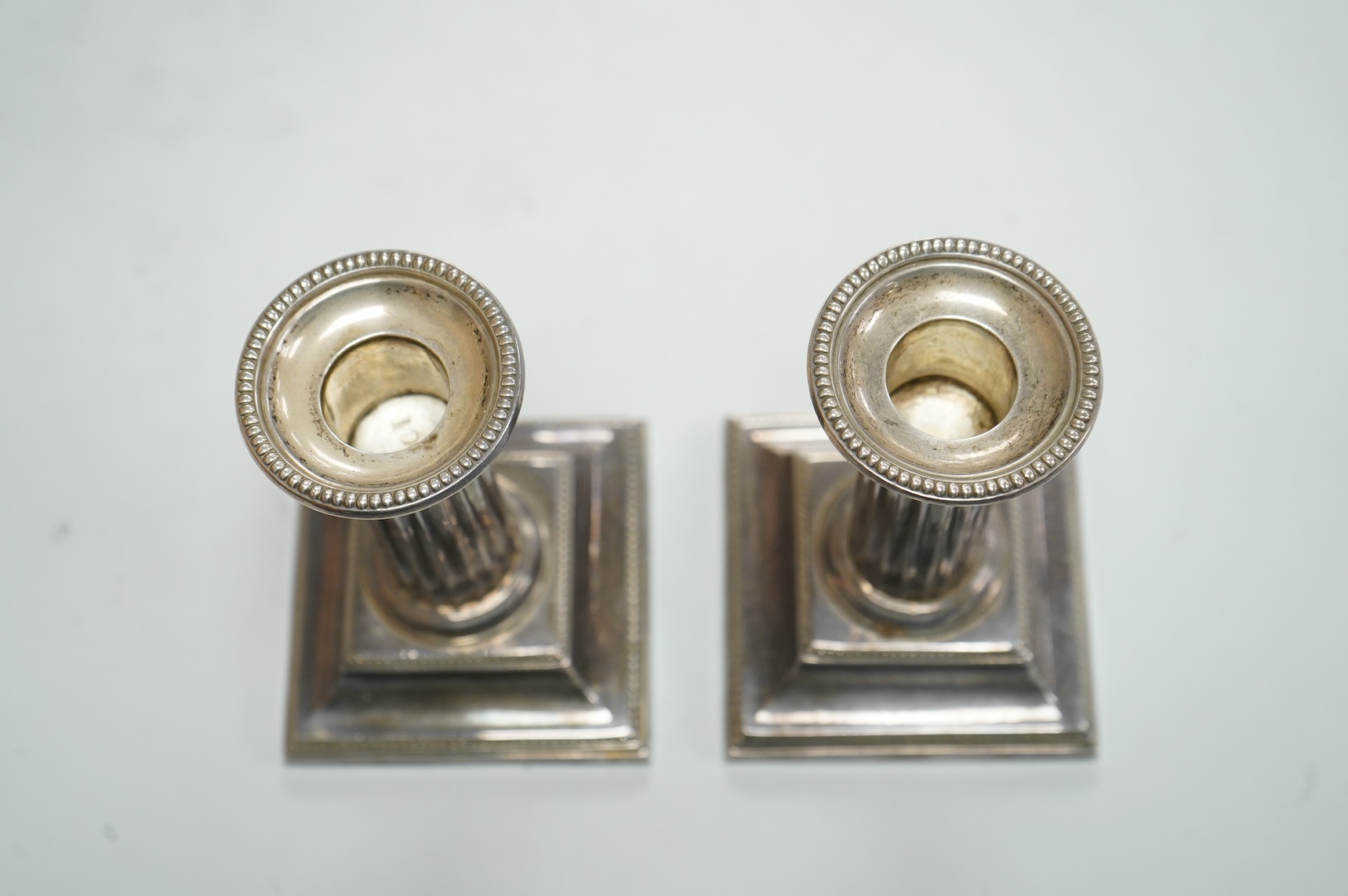 A pair of Edwardian silver mounted fluted column candlesticks, by Hawksworth, Eyre & Co, Sheffield, 1905/6, height 12cm, weighted.
